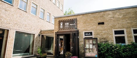 A building with a brick facade, large windows, and a sign that reads "8 MECKE BACH."