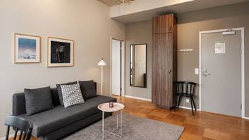 A modern living room with a grey sofa, a small round table, and a mirror.
