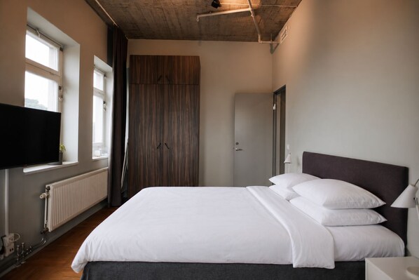 Un dormitorio con cama, televisor, armario y radiador.