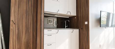 A modern kitchen with white cabinets, a black faucet, and a built-in oven.