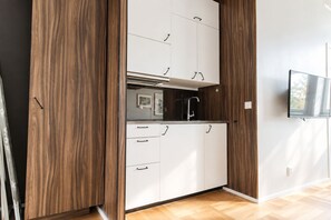 A modern kitchen with white cabinets, a black faucet, and a built-in oven. - Second Home Hotel & Apartments (Solna)