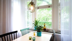 Un comedor con una mesa, sillas, una lámpara colgante y un ventanal con vistas a zonas verdes.