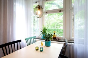 Un comedor con una mesa, sillas, una lámpara colgante y un ventanal con vistas a zonas verdes.