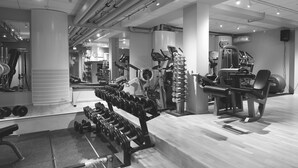 Un gimnasio con diverso equipo de ejercicio, incluyendo mancuernas, una cinta de correr y máquinas de pesas.