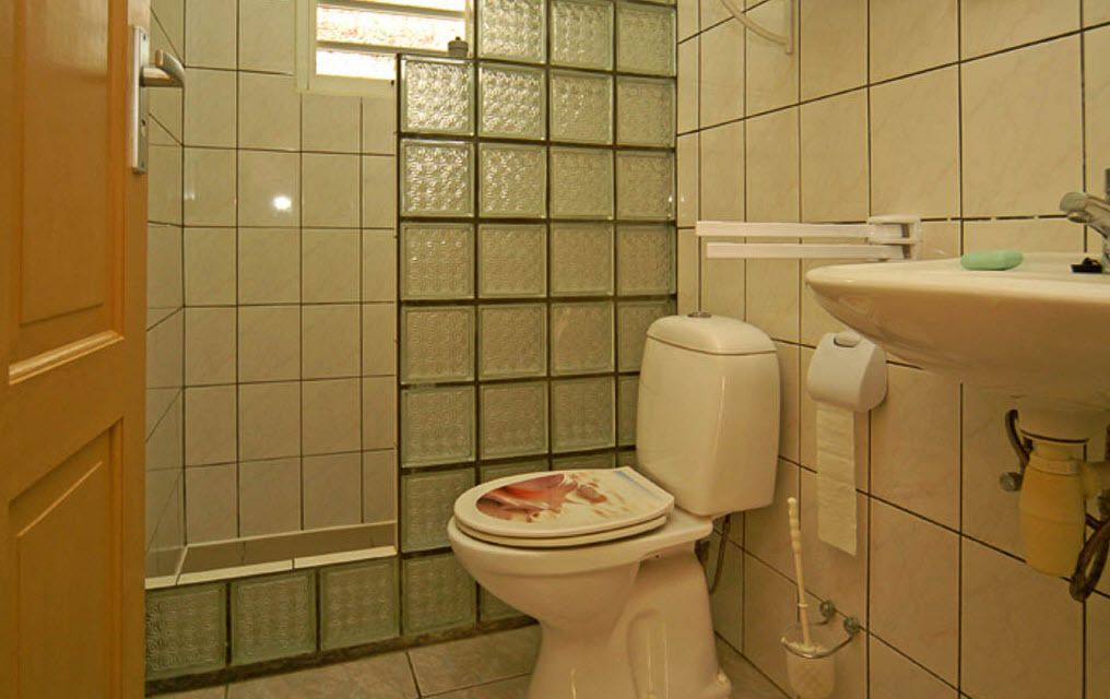 A bathroom with a toilet, a sink, and a shower area with tiled walls.