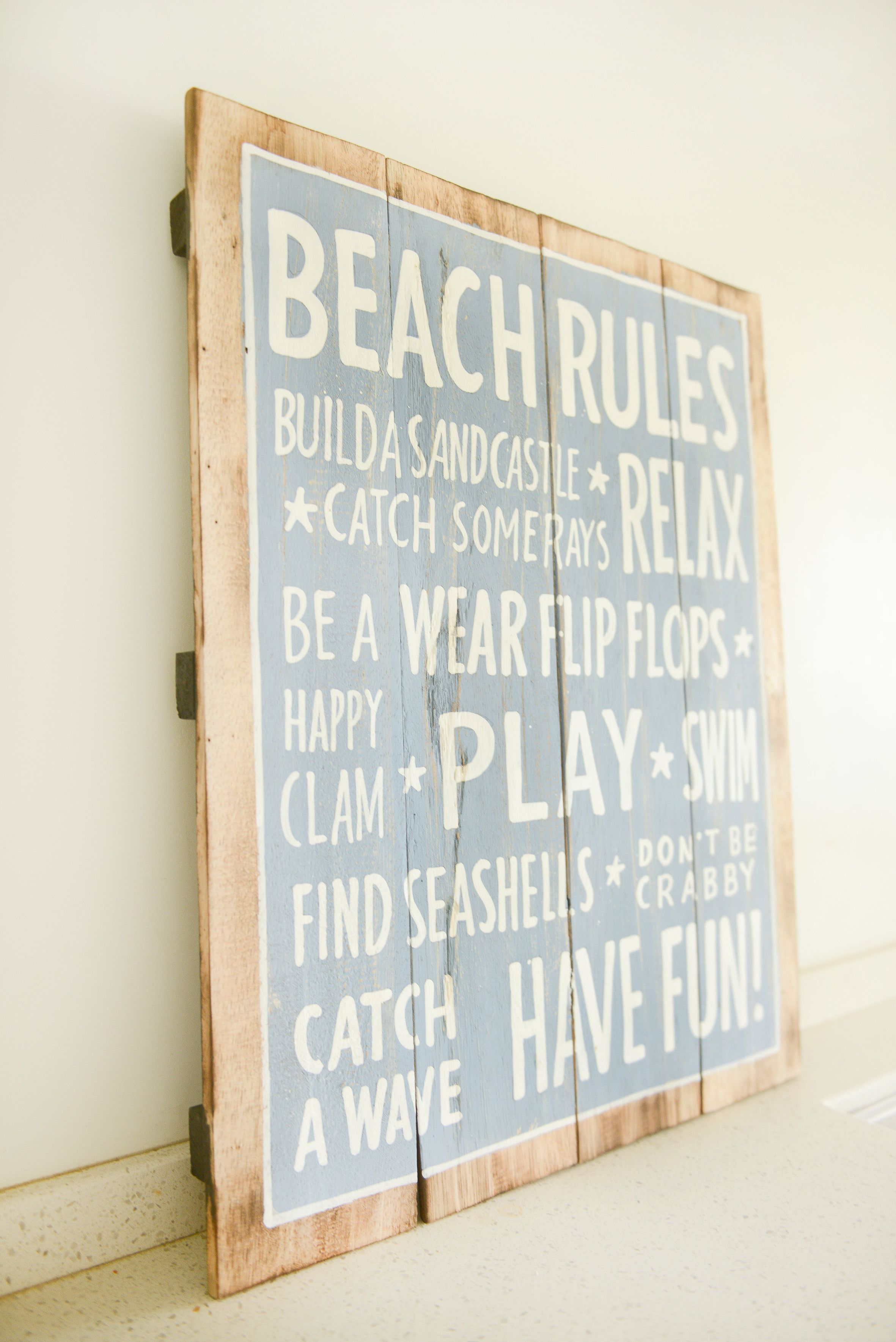 Un letrero de madera con la leyenda 'BEACH RULES' en letras grandes.
