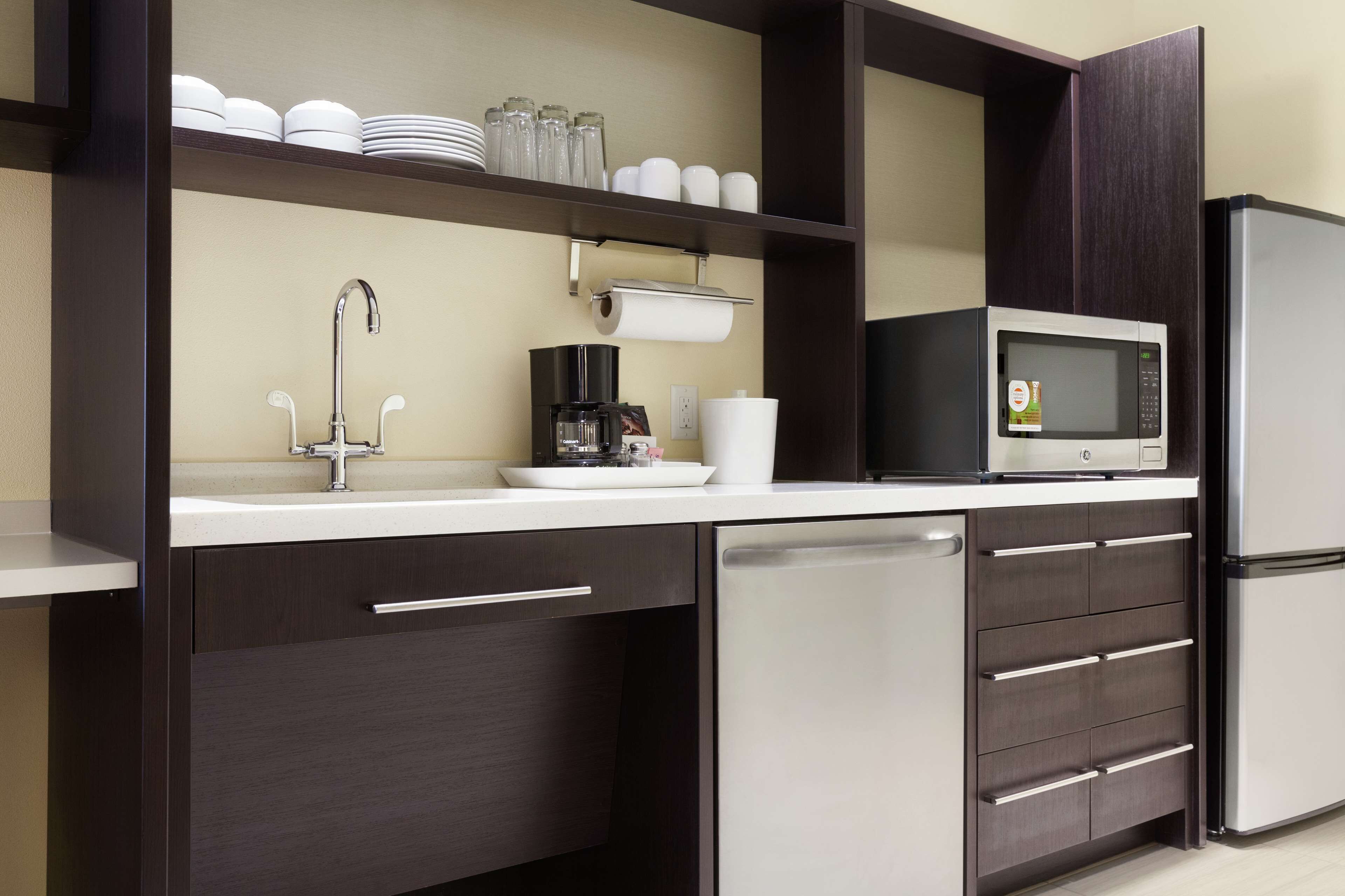 A modern kitchen with a dishwasher, microwave, coffee maker, and a sink.