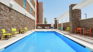 Una piscina al aire libre, sillones reclinables de piscina