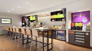 A modern hotel kitchen with a long bar area, a coffee station, and a trash bin.