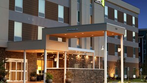 A hotel entrance with a covered outdoor area, stone facade, and multiple windows.