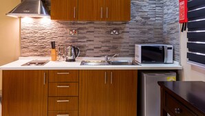 A modern kitchen with wooden cabinets, a stainless steel range hood, a microwave, and a built-in sink. - Eagle's (Accra)