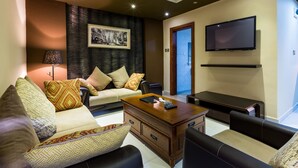 A modern living room with a sofa, coffee table, and a flat-screen TV mounted on the wall. - Eagle's (Accra)