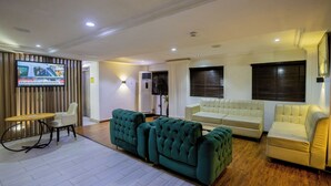A modern living room with a television, sofas, and a dining area. - GolfView Suites & Conference Center (Lagos)