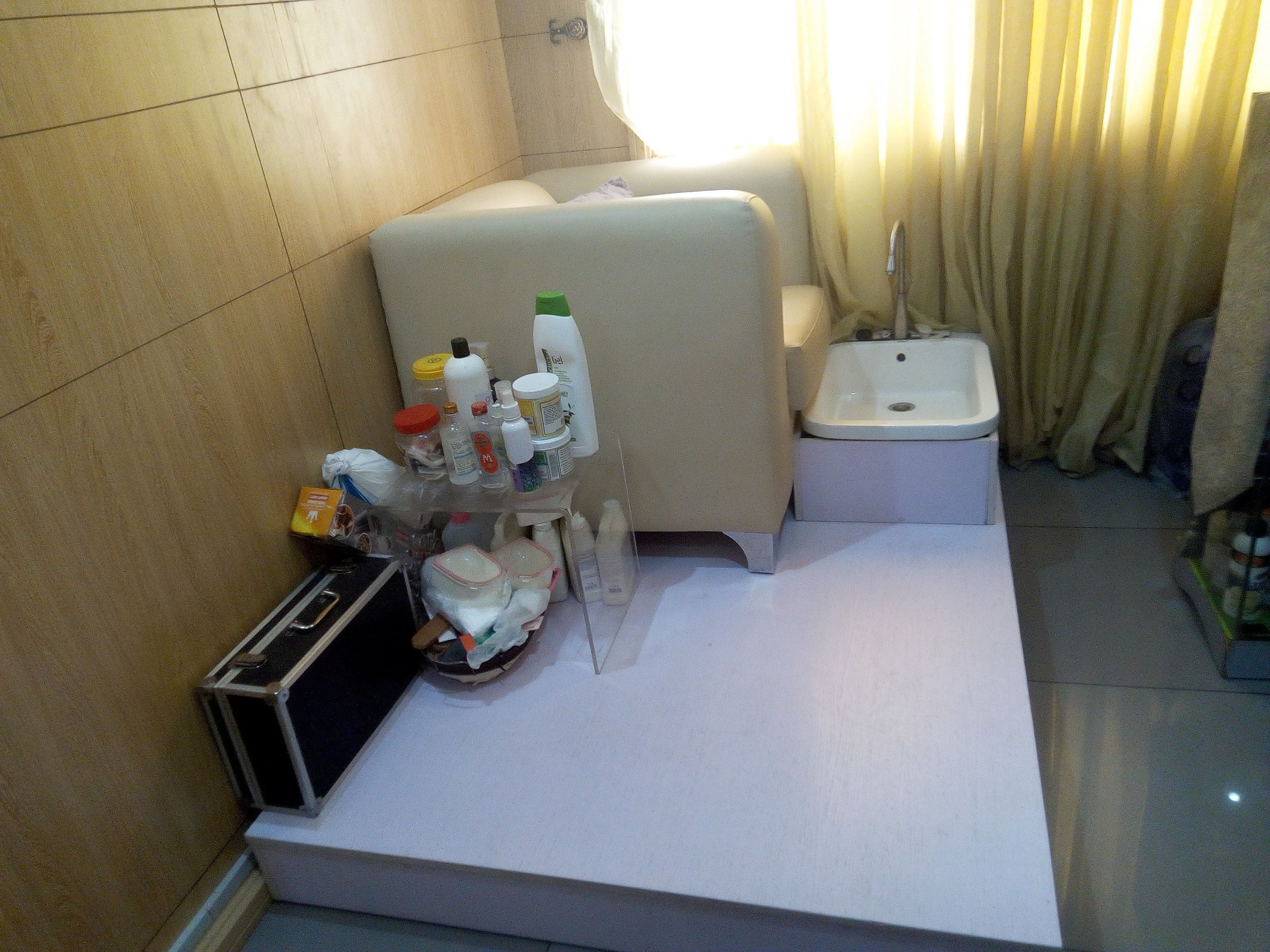 A hotel room with a bed, a small bedside table, a portable heater, and a bathroom area with a sink and toilet.