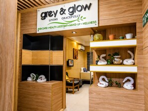 Un centro de bienestar con un letrero que dice 'grey & glow' y que anuncia servicios como cuidado de la piel, bar de jugos saludables, maquillaje y bienestar.