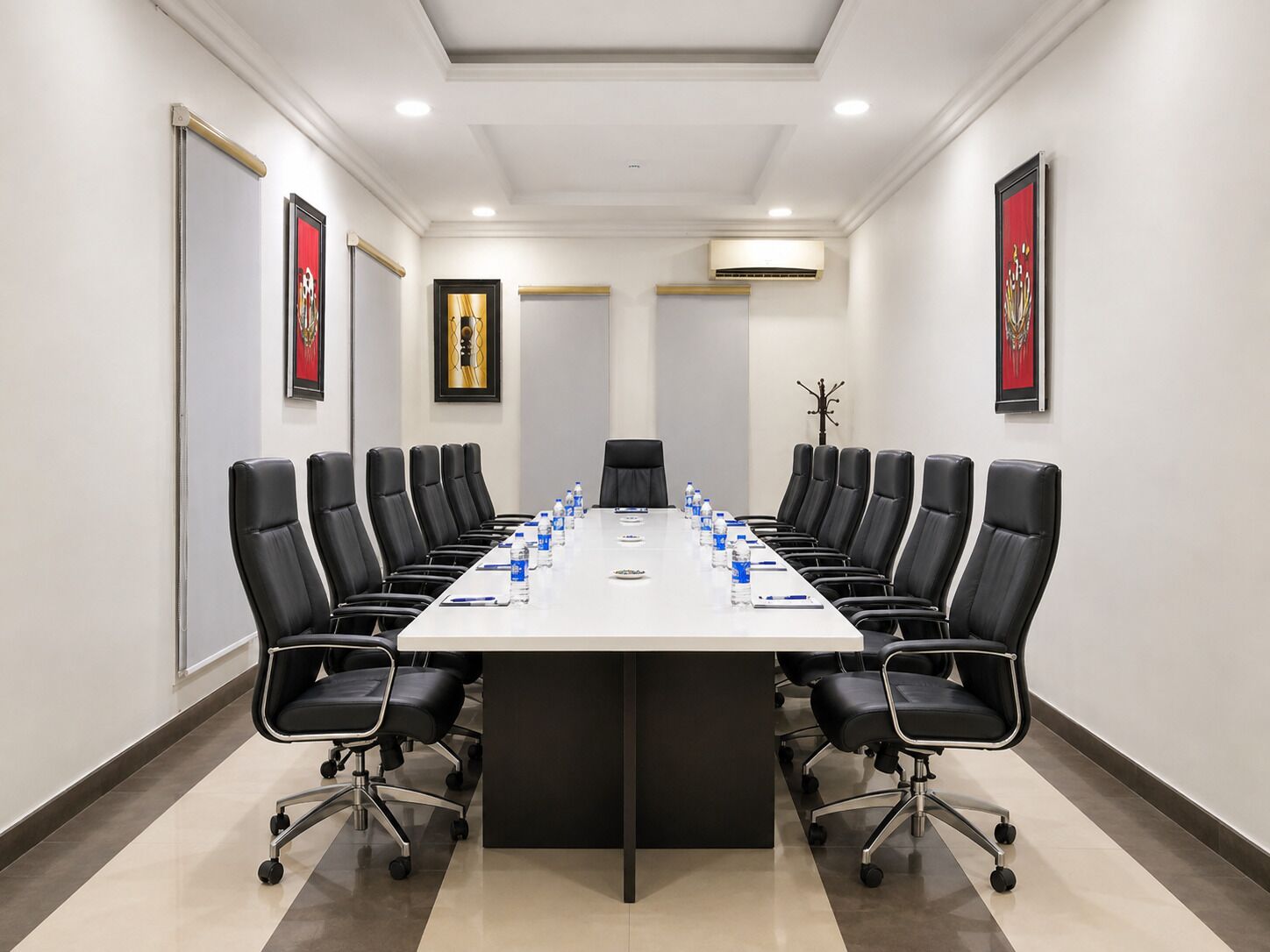 A conference room with a long table, black chairs, and water bottles.
