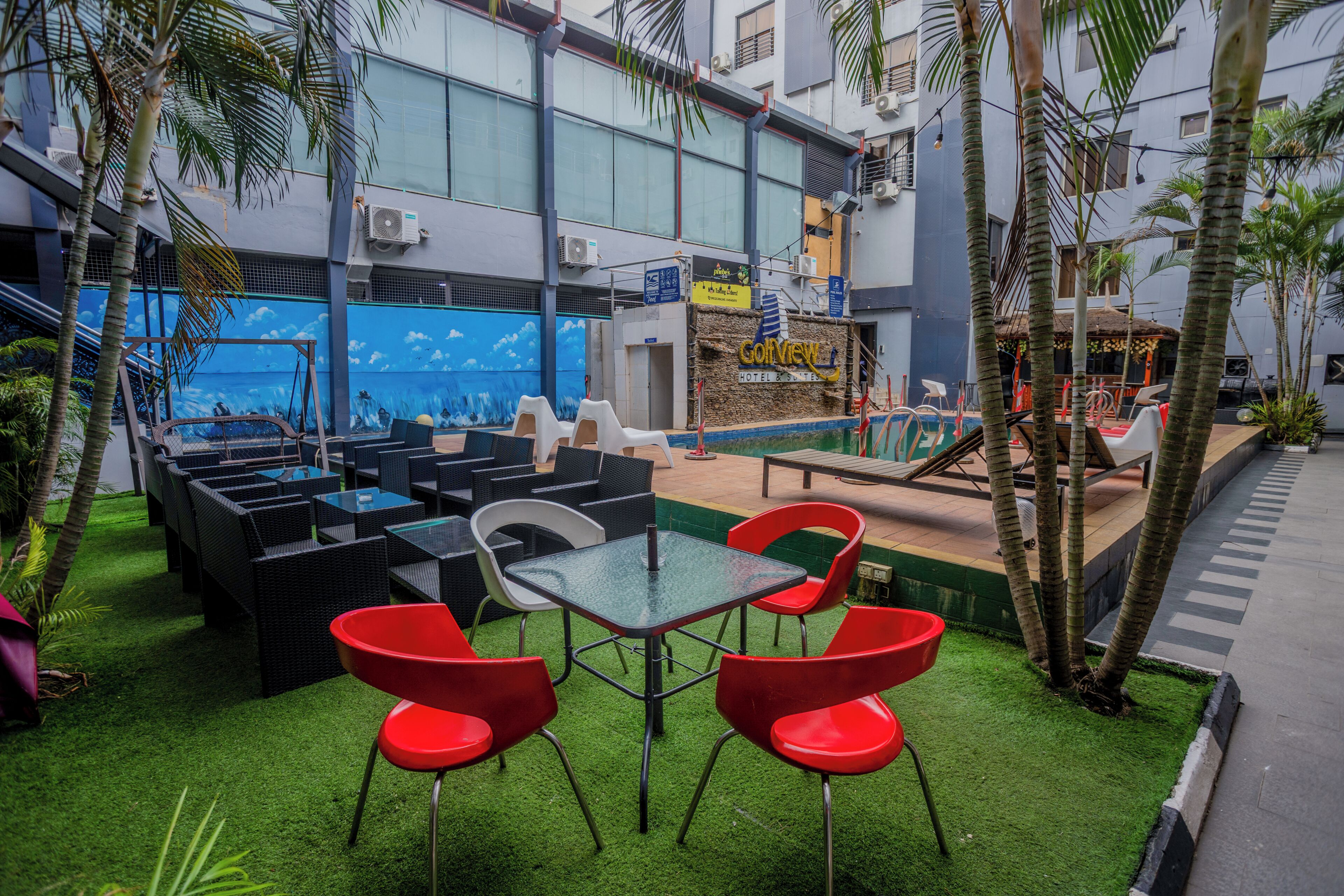 A rooftop bar with outdoor seating, a pool, and a view of the cityscape.