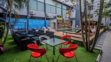 A rooftop bar with outdoor seating, a pool, and a view of the cityscape.