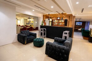A hotel lobby with seating, a bar area, and a television screen. - GolfView Suites & Conference Center (Lagos)