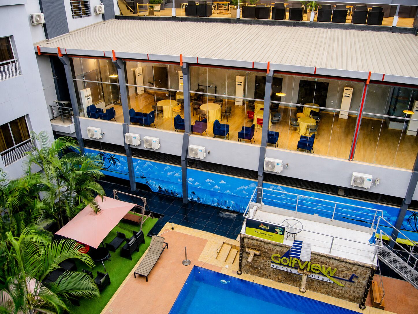 A hotel with a pool area, indoor seating, and a view of the pool.