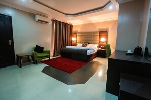 Ein Hotelzimmer mit Bett, Nachttisch, Lampe und Schreibtisch mit Stuhl.
