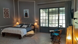 A bedroom with a bed, two bedside lamps, a chair, a floor lamp, and a large window with curtains. - Gala Da Vittoria (Ponta Delgada)