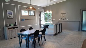 A modern kitchen with a dining area, wooden herringbone flooring, pendant lighting, and a view of the outdoors. - Gala Da Vittoria (Ponta Delgada)