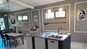 A modern kitchen with a central island, a dining area with chairs, and a television on the wall. - Gala Da Vittoria (Ponta Delgada)
