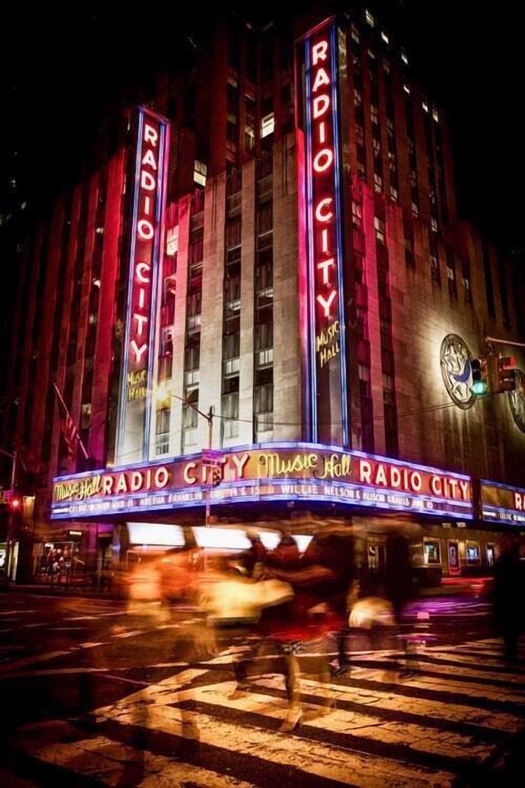 Un edificio con insegna "RADIO CITY", caratterizzato da una grande marcatura luminosa e diverse insegne verticali.
