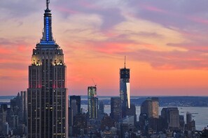 Un horizonte urbano con rascacielos destacados, incluyendo un edificio bien iluminado con una aguja distintiva.