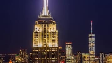 Un paisaje urbano nocturno con rascacielos iluminados, incluyendo un edificio destacado con aguja.