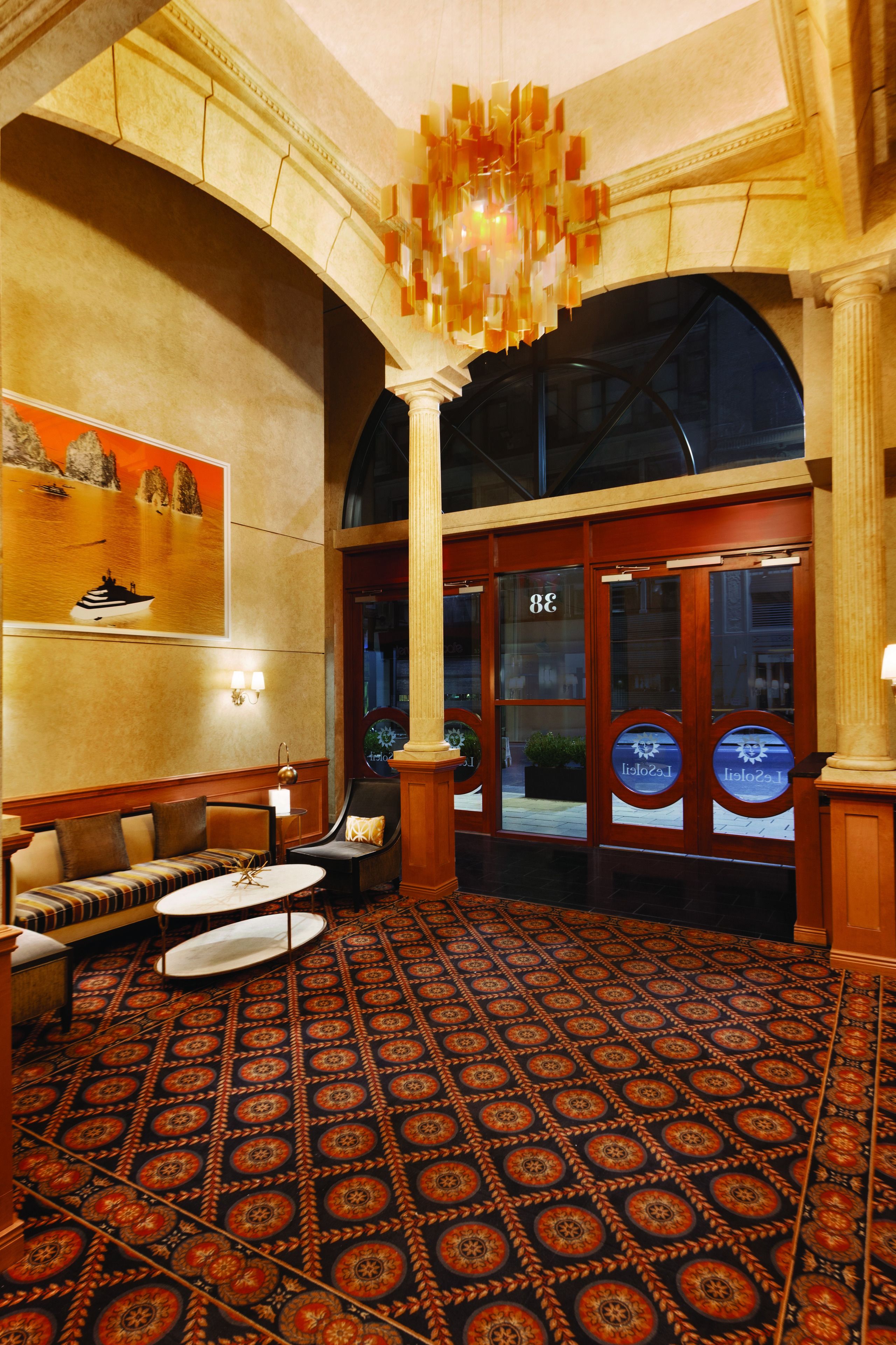 Eine Lobby mit einem gemusterten Teppich, einer Sitzecke und einer großen Chandelier.