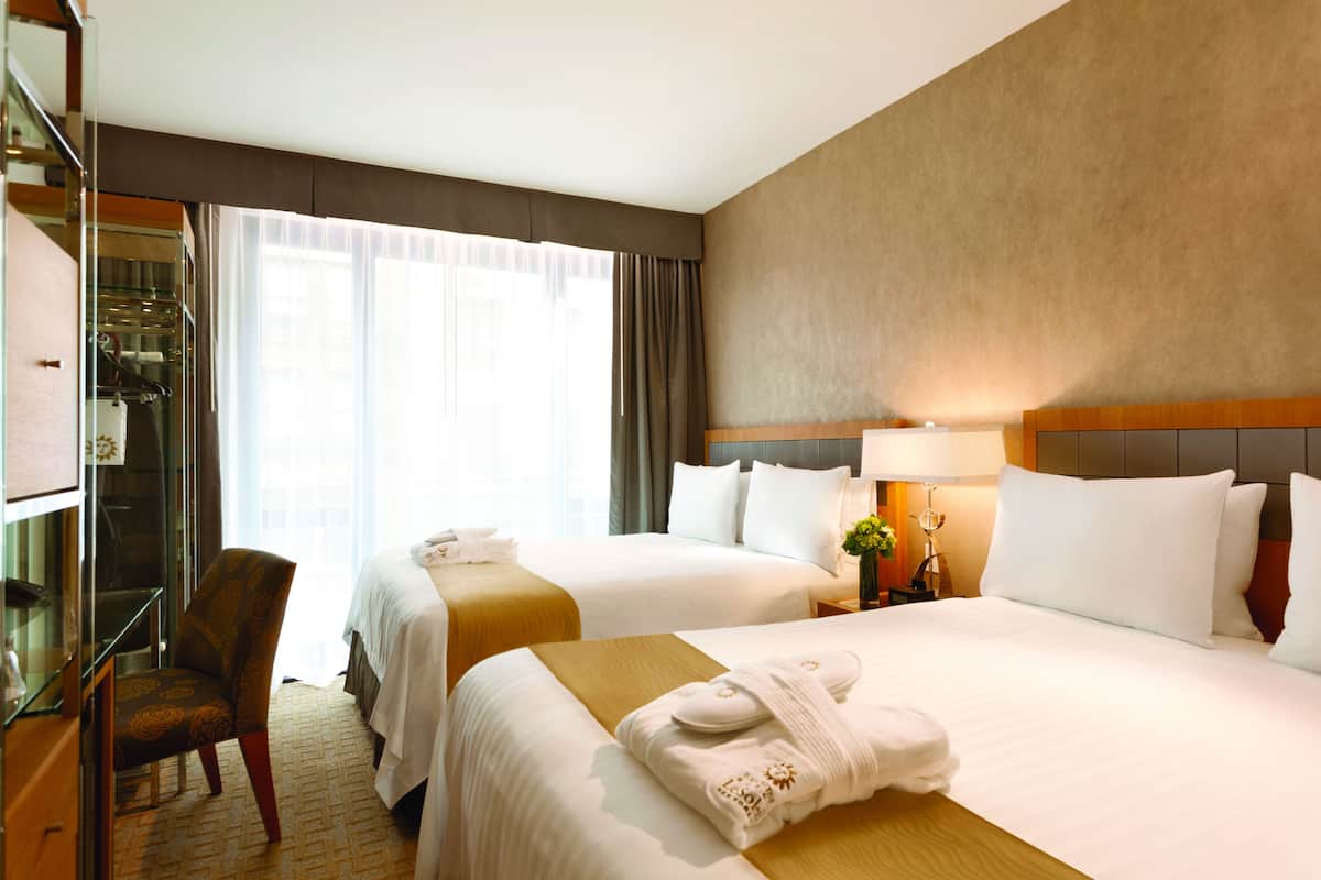 Une chambre d’hôtel avec deux lits, un bureau et une chaise.