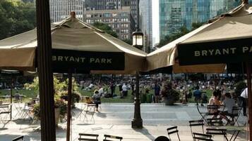 Un espacio al aire libre con mesas y sillas, una farola y un letrero que dice "BRYANT PARK".