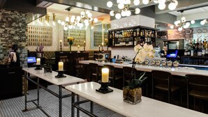 Een bar met verschillende zithoeken, een bar en een ruim assortiment flessen en glazen.
