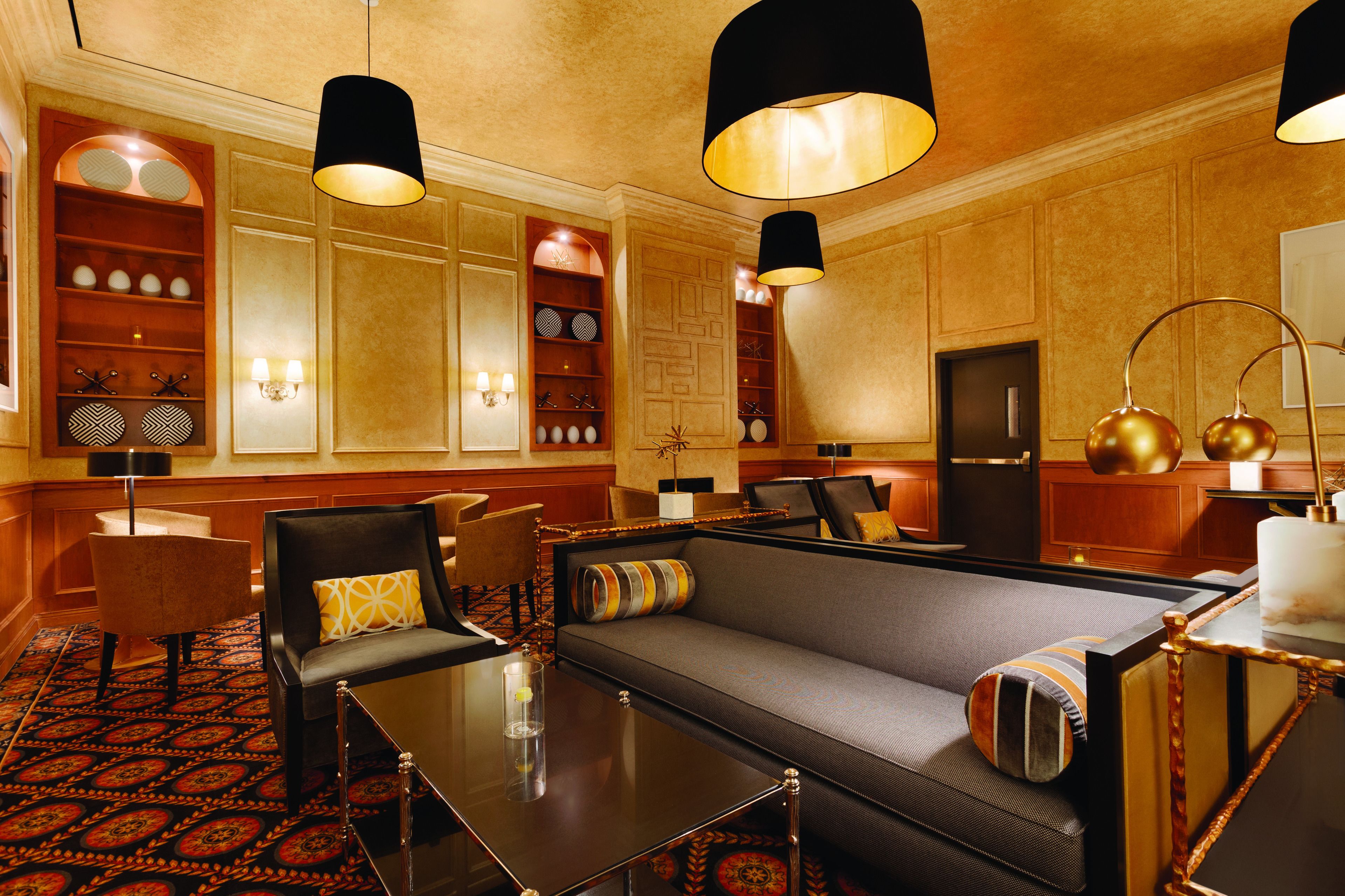 Un elegante hall de hotel con un sofá, sillones, una mesita de café y un televisor.
