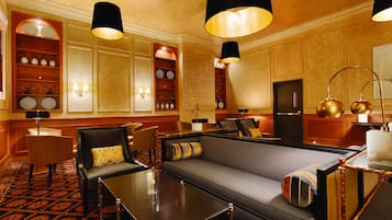 Un elegante hall de hotel con un sofá, sillones, una mesita de café y un televisor.
