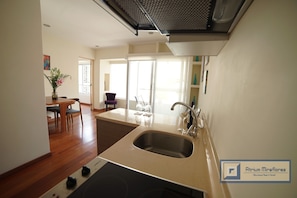A modern kitchen with a built-in dishwasher, a sink, and a dining area with a table and chairs. - Atrium Miraflores (Lima)