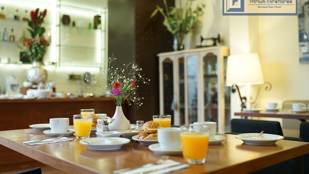 Una escena de desayuno con una mesa de madera, platos, tazas y un jarrón con flores.