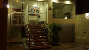 Un edificio moderno con una escalera que conduce a un segundo piso, un garaje y una entrada con puerta de cristal.