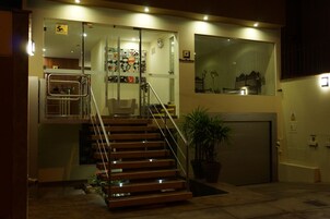 A modern building with a staircase leading to a second floor, a garage, and a glass door entrance.