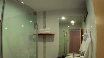 A modern bathroom with a glass shower enclosure, a toilet, a sink with a mirror, and a towel rack.