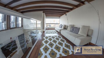 Un salón moderno con un sofá, un tapiz estampado y un balcón con vistas a la ciudad.
