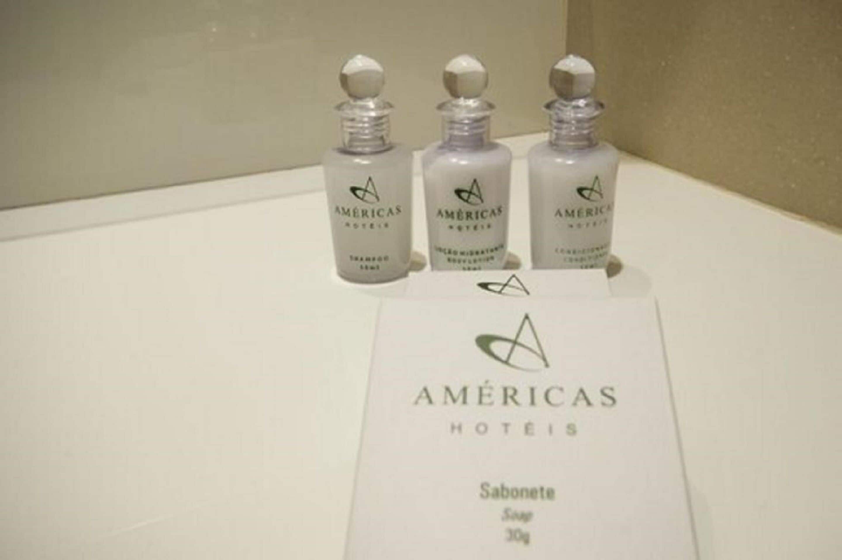 Trois flacons de produits de toilette avec une étiquette indiquant « AMÉRICAS HOTÉIS ».