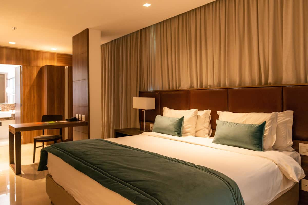 A hotel room with a large bed, a desk, and a chair.