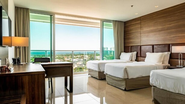 Quarto de hotel com duas camas, uma escrivaninha e vista para a cidade.