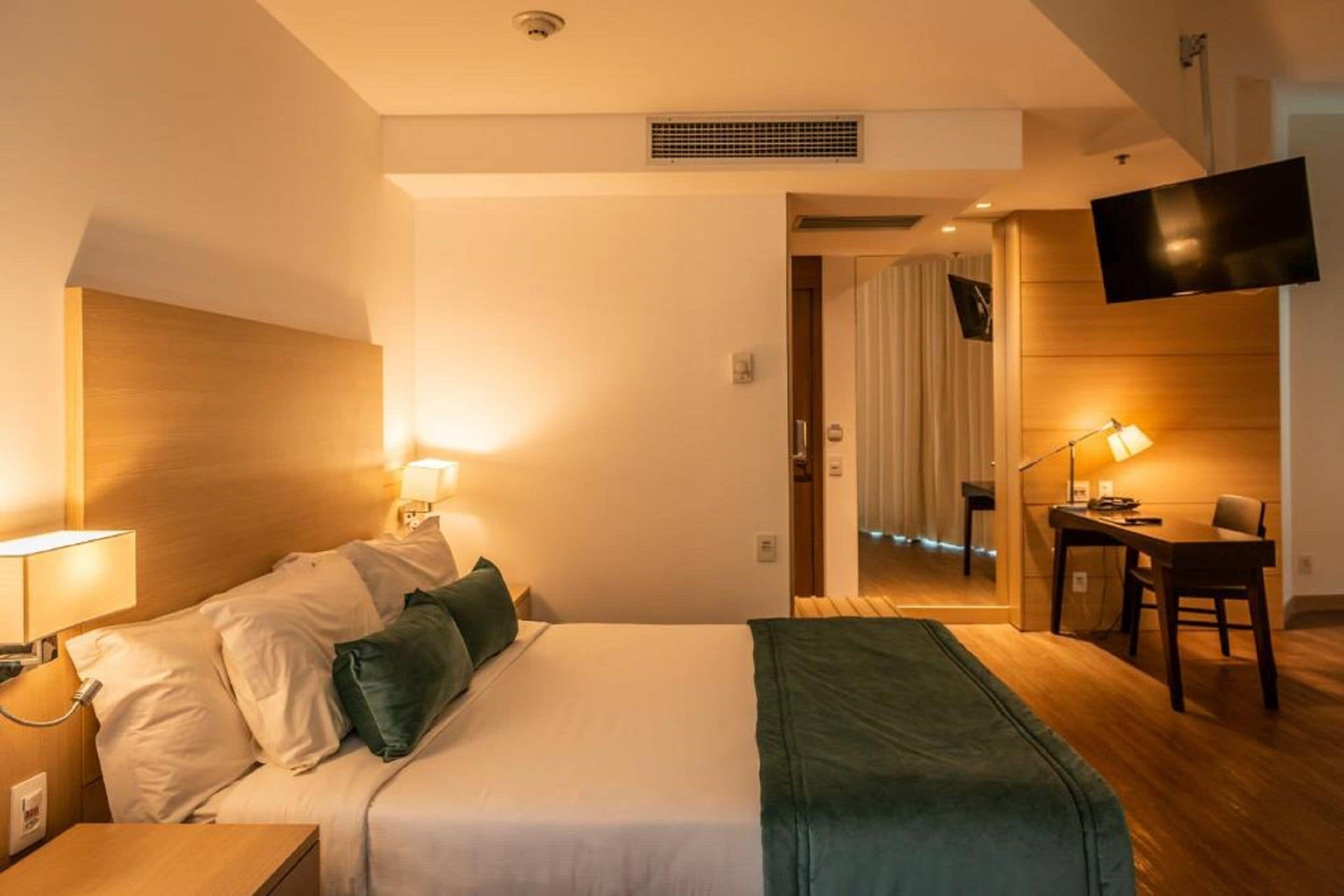 Una habitación de hotel con cama, mesita de noche, lámpara y escritorio con silla.