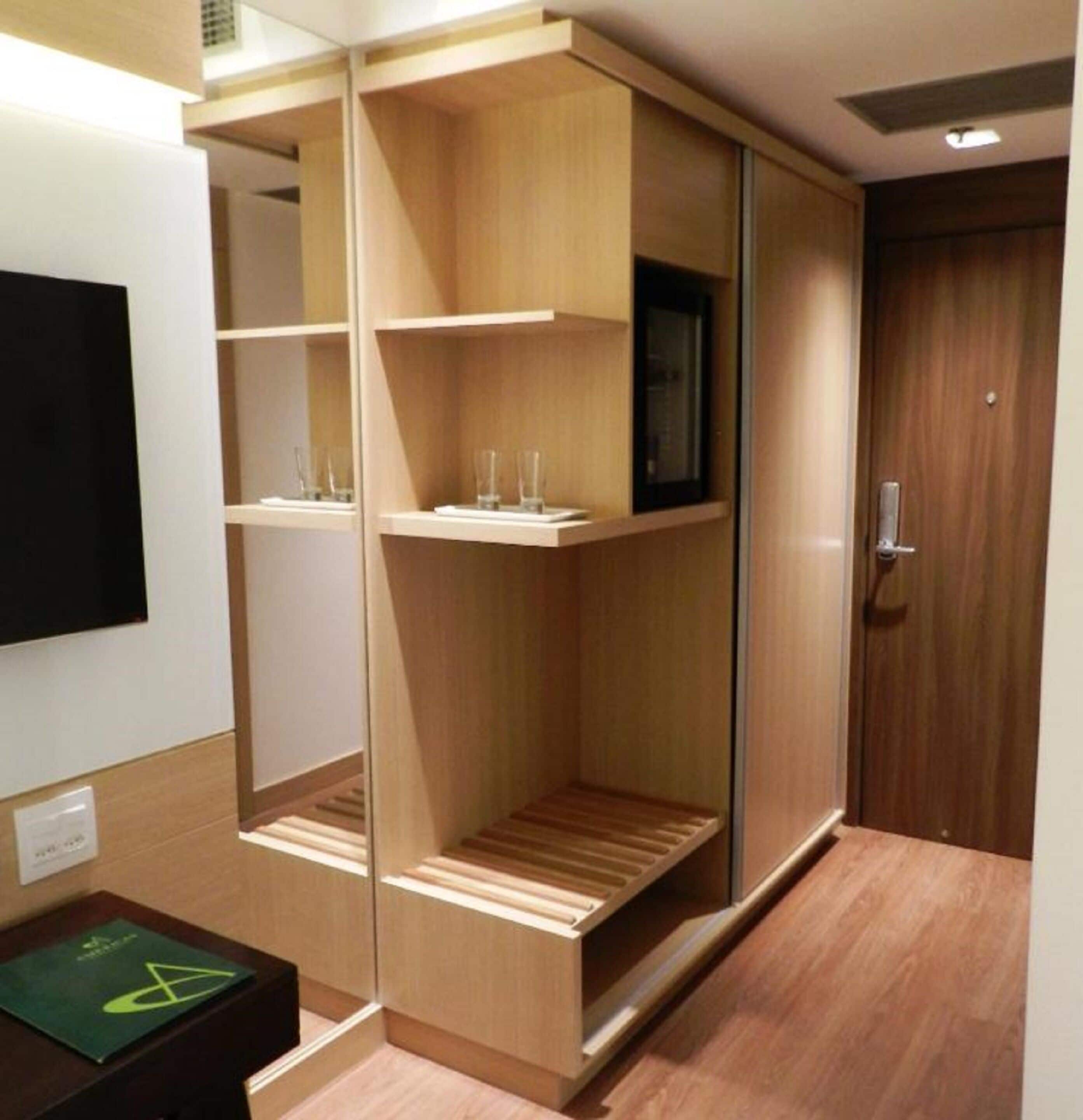 A modern room with built-in wooden shelving units, a flat-screen TV mounted on the wall, and a wooden door.