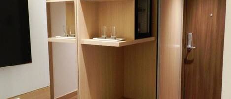 A modern room with built-in wooden shelving units, a flat-screen TV mounted on the wall, and a wooden door.