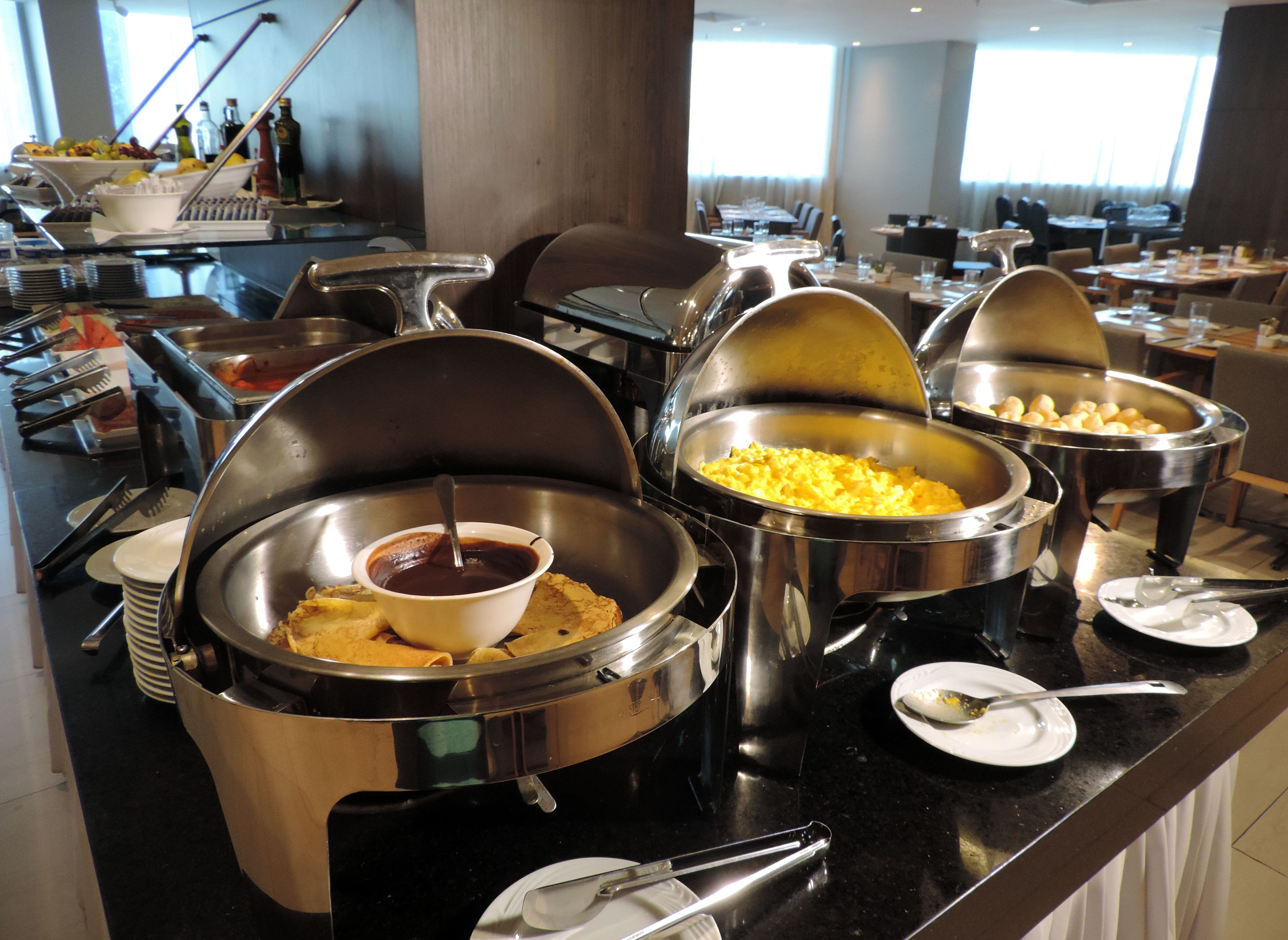 A buffet setup with various food items in large metal containers, including a bowl of soup and a dish of scrambled eggs.